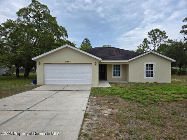 single story home with a garage, concrete driveway, stucco siding, and a front yard