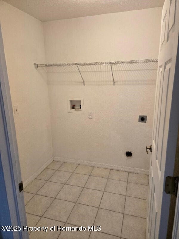 laundry room with hookup for an electric dryer, hookup for a washing machine, baseboards, and light tile patterned flooring