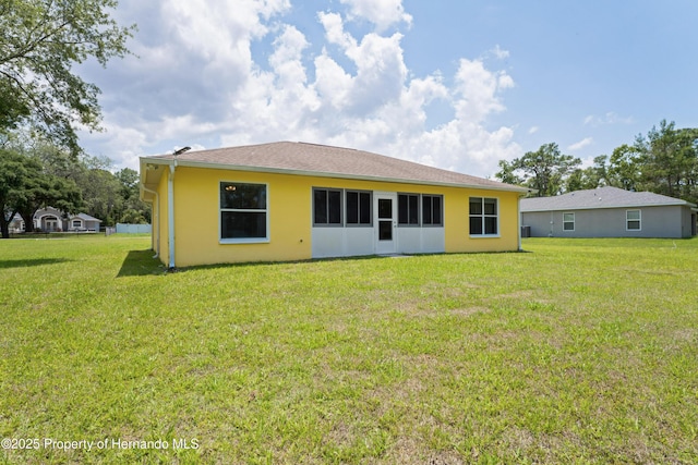 12271 House Finch Rd, Weeki Wachee, FL 34614 - rear view of house featuring a lawn and stucco siding