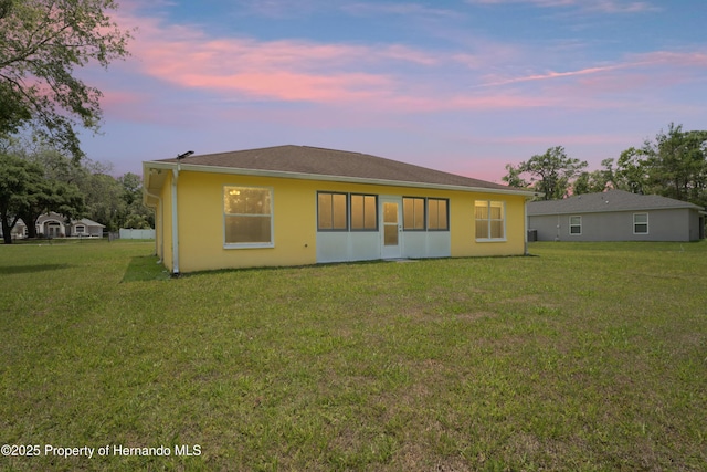 12271 House Finch Rd, Weeki Wachee, FL 34614 - back of property at dusk with a yard and stucco siding