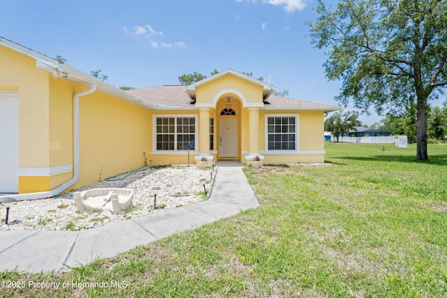 12271 House Finch Rd, Weeki Wachee, FL 34614 - view of front of property with stucco siding, a front yard, and roof with shingles