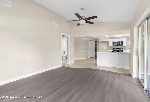 unfurnished living room featuring a ceiling fan, light wood-style floors, baseboards, a sink, and high vaulted ceiling