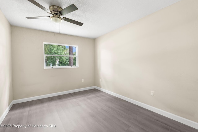 spare room with wood finished floors, a ceiling fan, baseboards, and a textured ceiling