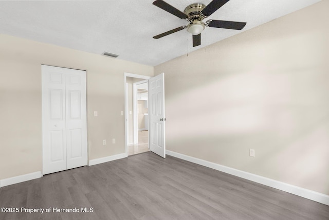 unfurnished bedroom featuring wood finished floors, baseboards, a closet, and ceiling fan