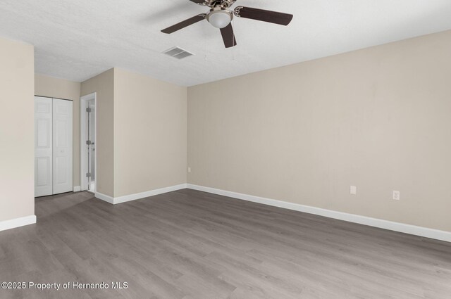 unfurnished room with wood finished floors, a ceiling fan, and baseboards