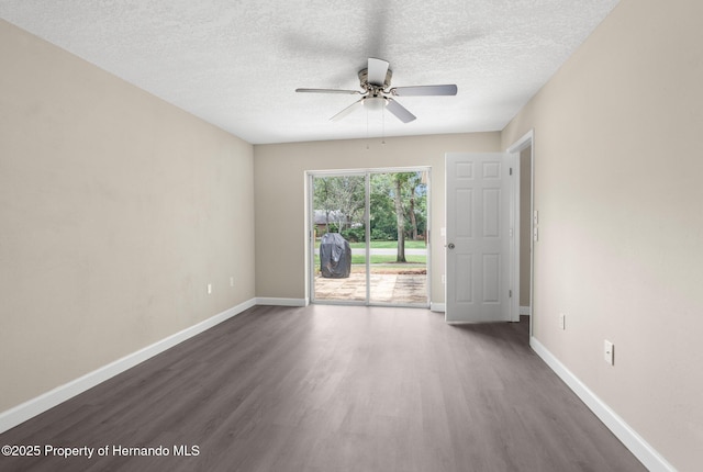 spare room featuring dark wood finished floors, a ceiling fan, a textured ceiling, and baseboards