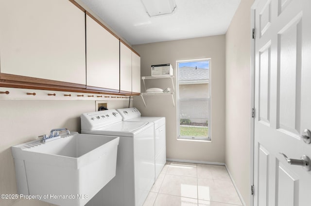 clothes washing area with cabinet space, washer and clothes dryer, light tile patterned floors, and baseboards