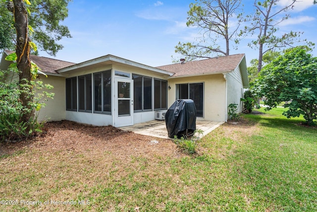 rear view of house featuring a sunroom, stucco siding, a yard, and a shingled roof