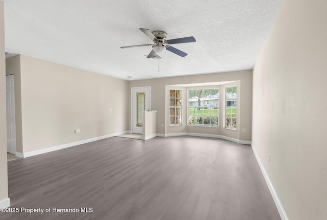 spare room with wood finished floors, a ceiling fan, a textured ceiling, and baseboards