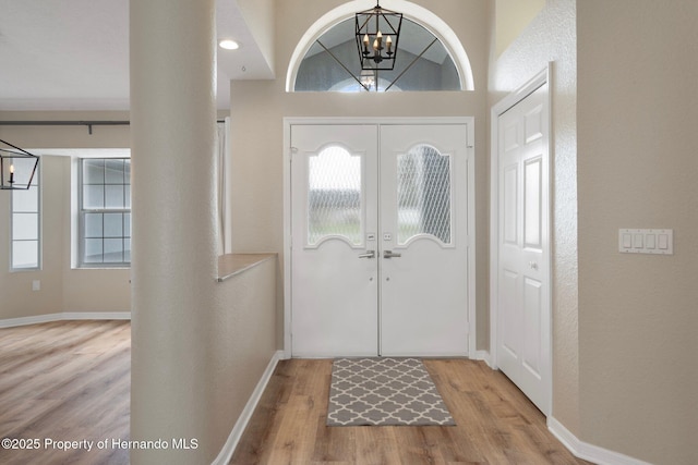 entrance foyer featuring a chandelier, wood finished floors, plenty of natural light, and baseboards