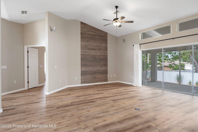spare room with high vaulted ceiling, a ceiling fan, wood finished floors, and baseboards