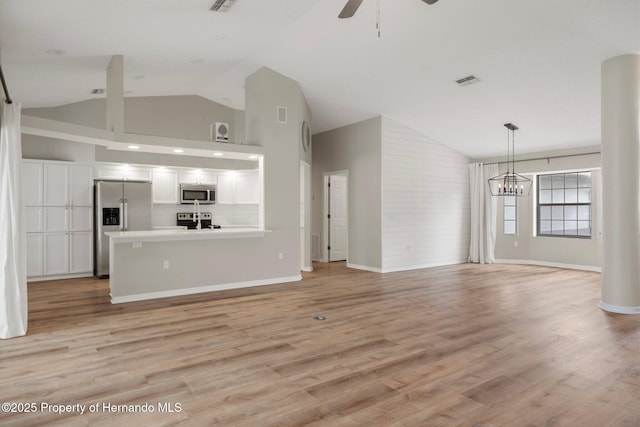unfurnished living room with a ceiling fan, light wood-type flooring, a chandelier, baseboards, and high vaulted ceiling