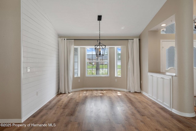 unfurnished dining area featuring a chandelier, wood finished floors, and baseboards
