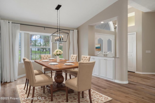 dining room featuring a chandelier, lofted ceiling, light wood-style flooring, and baseboards