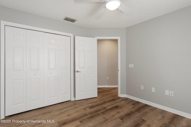 unfurnished bedroom with wood finished floors, baseboards, a closet, and a ceiling fan