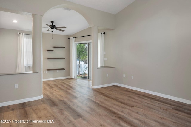 spare room featuring decorative columns, arched walkways, wood finished floors, baseboards, and recessed lighting