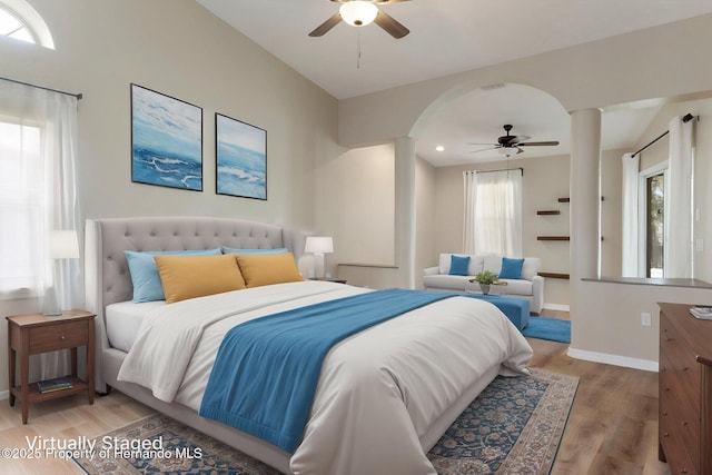 bedroom featuring ornate columns, light wood-style floors, baseboards, arched walkways, and recessed lighting