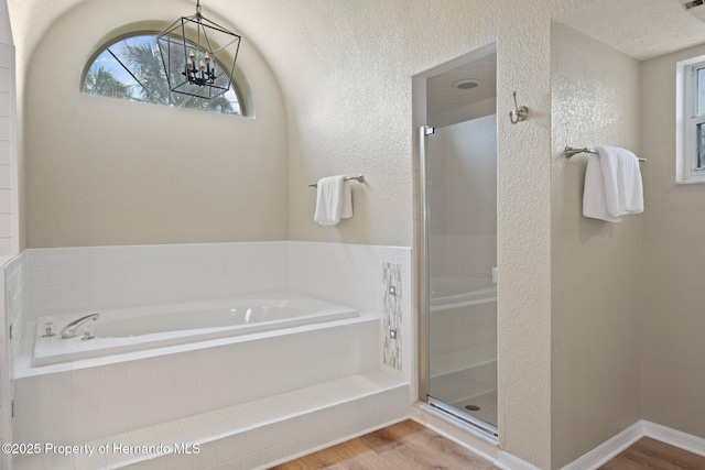 full bath with wood finished floors, a garden tub, a stall shower, and a textured wall