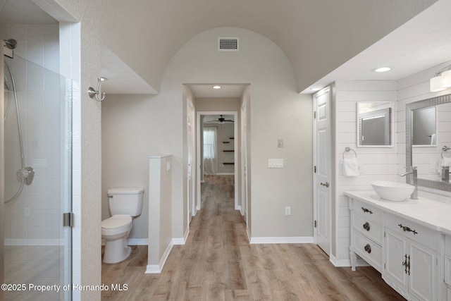 bathroom featuring toilet, a stall shower, wood finished floors, vanity, and recessed lighting