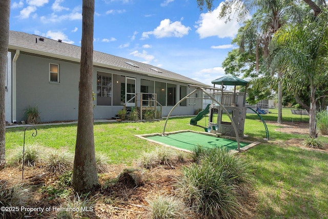 back of property featuring a playground, a sunroom, an area to practice putting, and roof with shingles