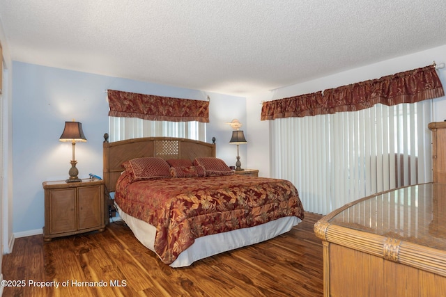 bedroom with wood finished floors, a textured ceiling, and baseboards