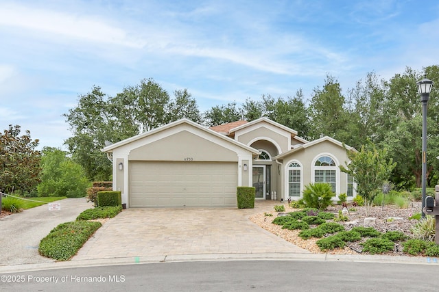 11750 Teapot Ct, Spring Hill, FL 34609 - ranch-style home featuring a garage, decorative driveway, and stucco siding