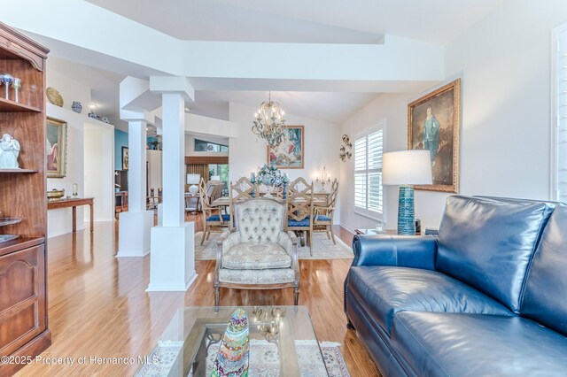 11750 Teapot Ct, Spring Hill, FL 34609 - living area with decorative columns, light wood-style flooring, lofted ceiling, baseboards, and a chandelier