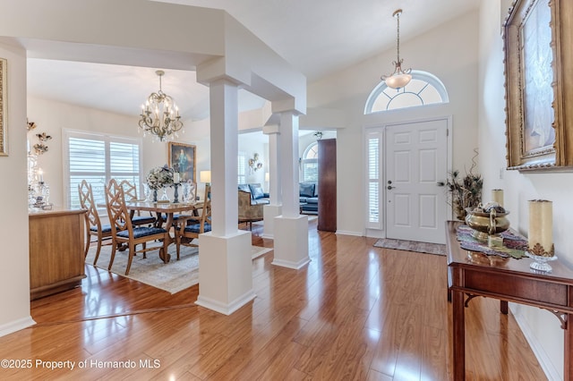11750 Teapot Ct, Spring Hill, FL 34609 - entrance foyer with light wood-style floors, a chandelier, vaulted ceiling, baseboards, and ornate columns