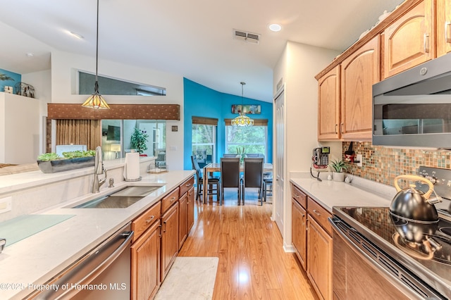 11750 Teapot Ct, Spring Hill, FL 34609 - kitchen featuring appliances with stainless steel finishes, a sink, vaulted ceiling, light wood finished floors, and decorative backsplash