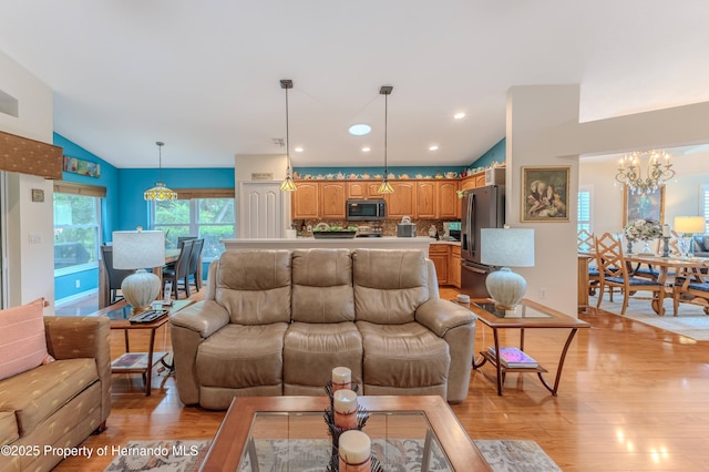 11750 Teapot Ct, Spring Hill, FL 34609 - living room with light wood-style floors, vaulted ceiling, and a chandelier