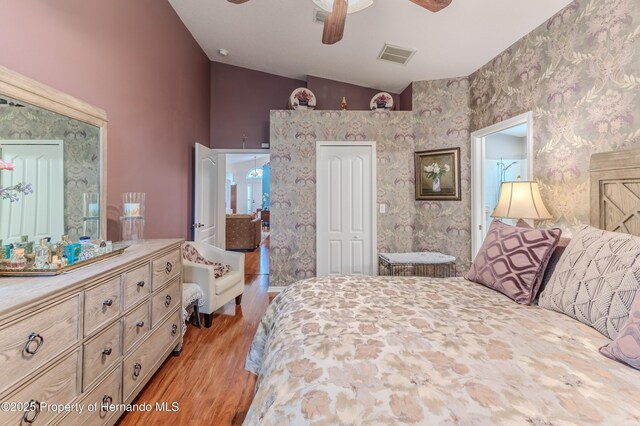 11750 Teapot Ct, Spring Hill, FL 34609 - bedroom with vaulted ceiling, light wood-type flooring, wallpapered walls, ceiling fan, and a closet