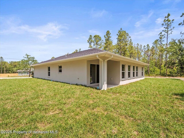 rear view of property featuring stucco siding, a yard, and a patio area