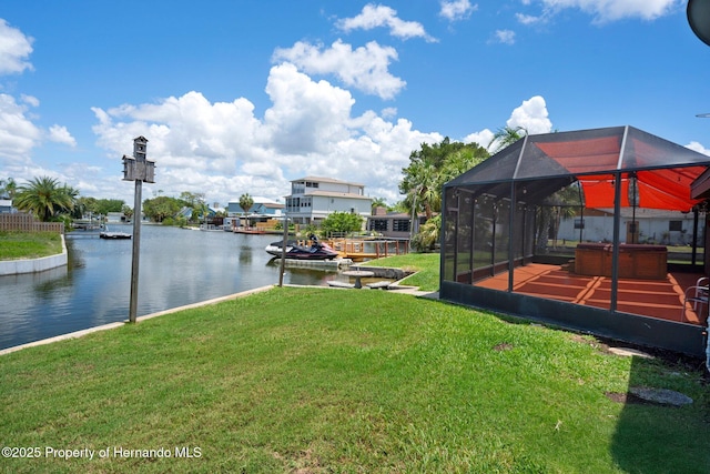 view of grassy yard featuring a water view and glass enclosure