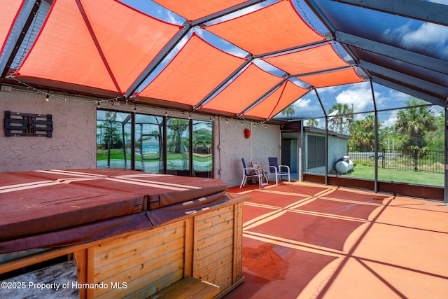 view of patio / terrace with a hot tub, fence, and a lanai