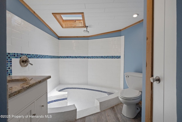 bathroom featuring toilet, vanity, wood finished floors, a bath, and lofted ceiling