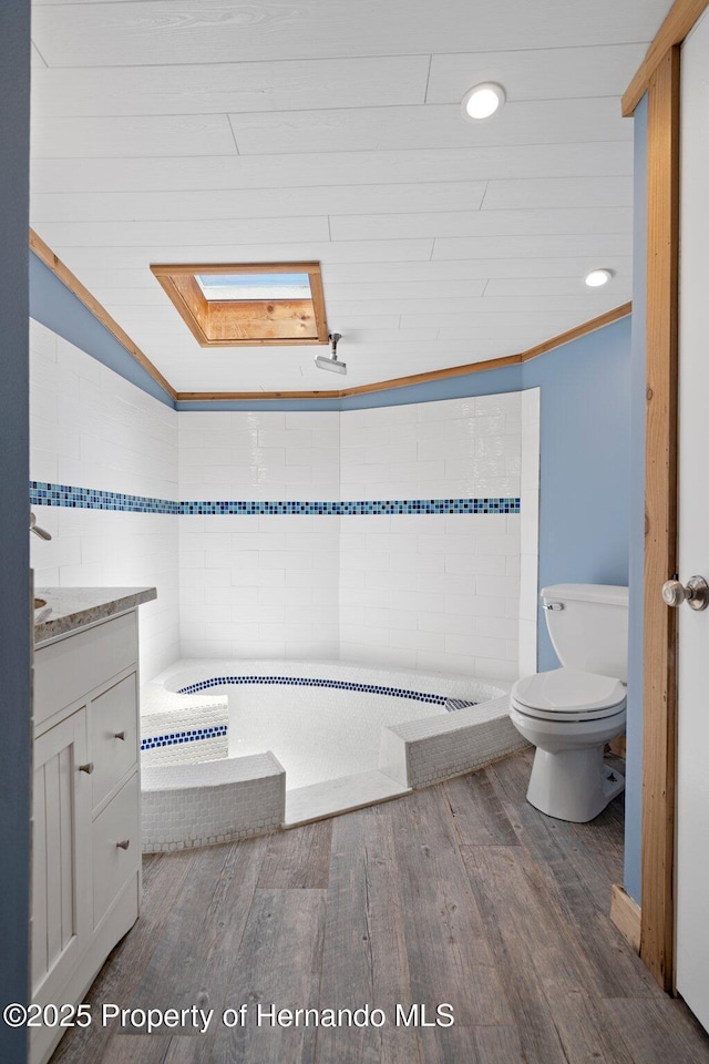 full bathroom with toilet, wood finished floors, vanity, a tub to relax in, and recessed lighting