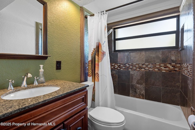 full bath with a textured wall, toilet, vanity, and shower / tub combo with curtain