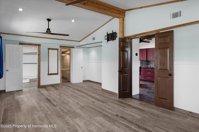 unfurnished bedroom with wainscoting, wood finished floors, baseboards, and connected bathroom