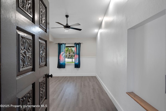 unfurnished room with ceiling fan, wood finished floors, and wainscoting