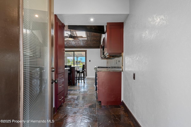 corridor with baseboards, stone tile floors, and a textured wall
