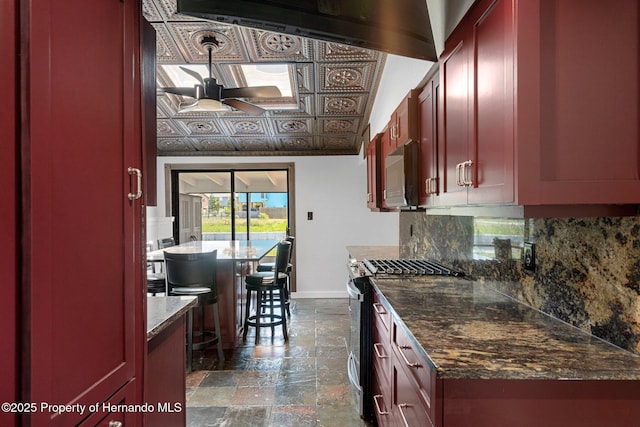 kitchen featuring stainless steel appliances, reddish brown cabinets, ceiling fan, baseboards, and decorative backsplash