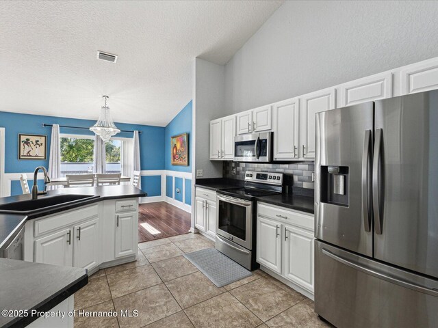6076 Shiprock Ave, Spring Hill, FL 34608 - kitchen featuring stainless steel appliances, dark countertops, a sink, lofted ceiling, and white cabinets