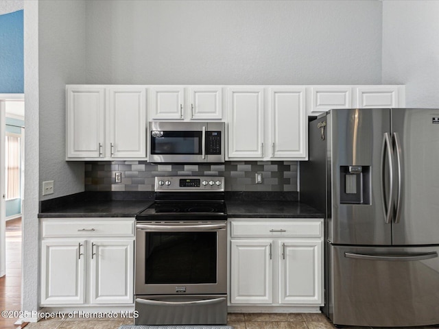 6076 Shiprock Ave, Spring Hill, FL 34608 - kitchen featuring stainless steel appliances, dark countertops, backsplash, and white cabinetry