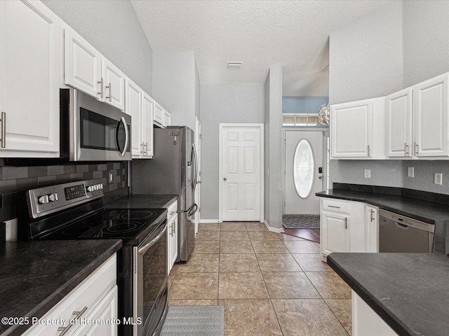 6076 Shiprock Ave, Spring Hill, FL 34608 - kitchen featuring appliances with stainless steel finishes, dark countertops, white cabinetry, a textured ceiling, and decorative backsplash