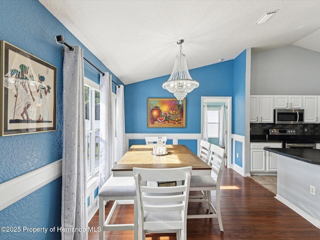 6076 Shiprock Ave, Spring Hill, FL 34608 - dining space with lofted ceiling, a chandelier, dark wood-style flooring, and a textured wall