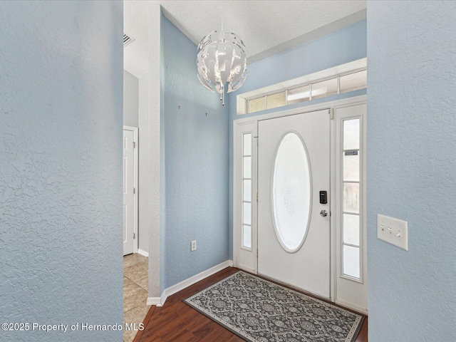 6076 Shiprock Ave, Spring Hill, FL 34608 - foyer entrance with a chandelier, a textured wall, wood finished floors, and baseboards