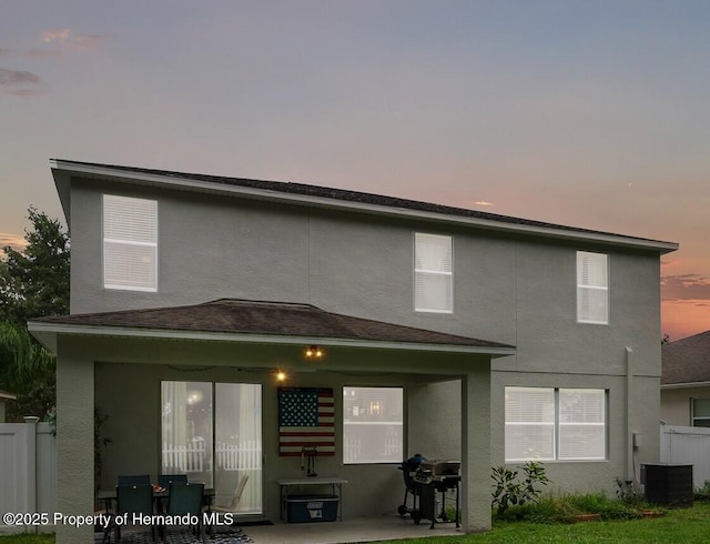 396 Winthrop Dr, Spring Hill, FL 34609 - back of property with stucco siding, a patio, central AC, and fence