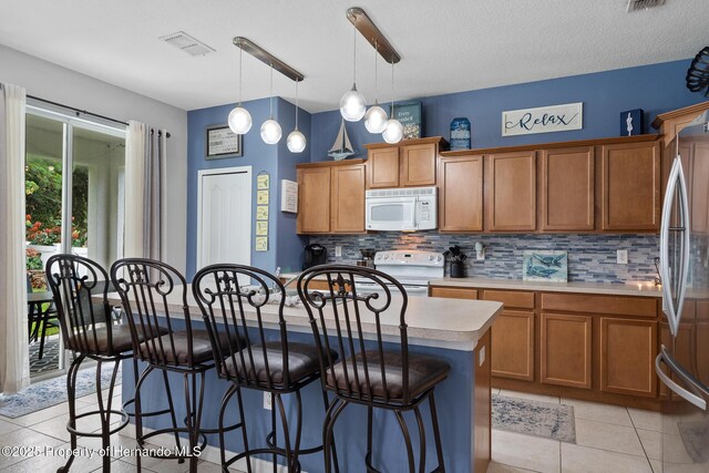 396 Winthrop Dr, Spring Hill, FL 34609 - kitchen featuring white appliances, backsplash, light countertops, a kitchen island, and brown cabinetry