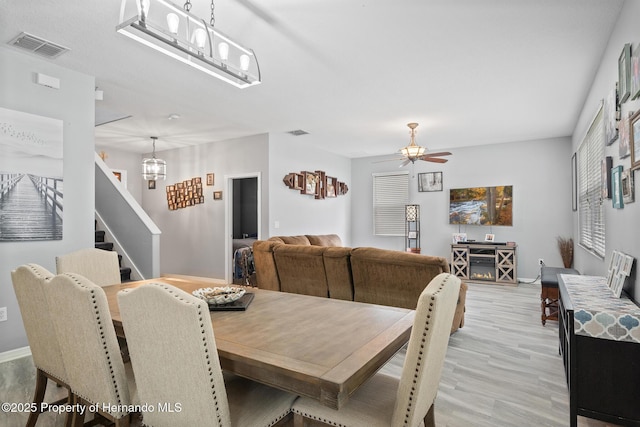 396 Winthrop Dr, Spring Hill, FL 34609 - dining space with a chandelier, baseboards, light wood finished floors, stairs, and a ceiling fan
