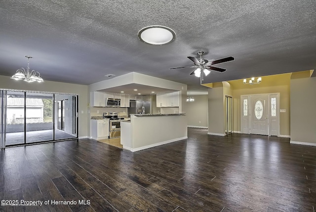 unfurnished living room featuring a chandelier, ceiling fan, a textured ceiling, wood finished floors, and baseboards